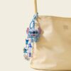 Blue alien backpack charm attached to a cream handbag